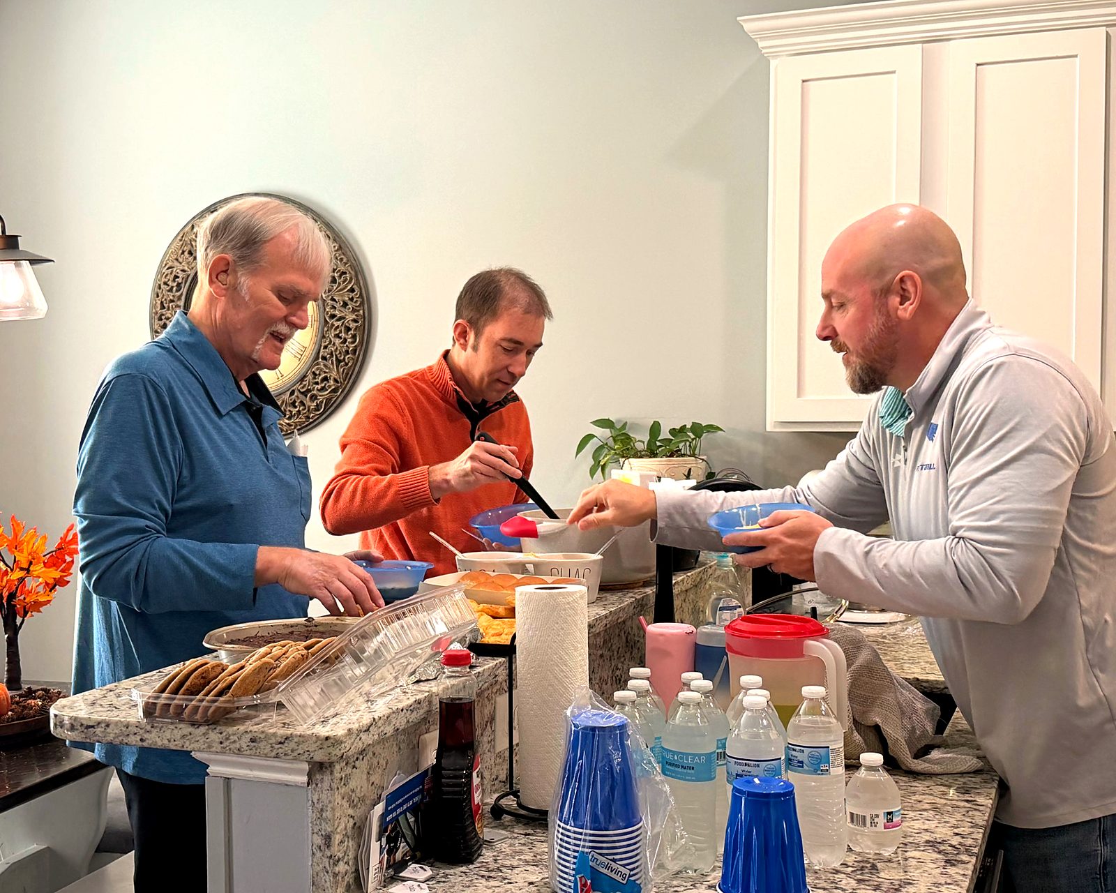 Friends serving themselves dinner in a kitchen at a Mosaic gathering
